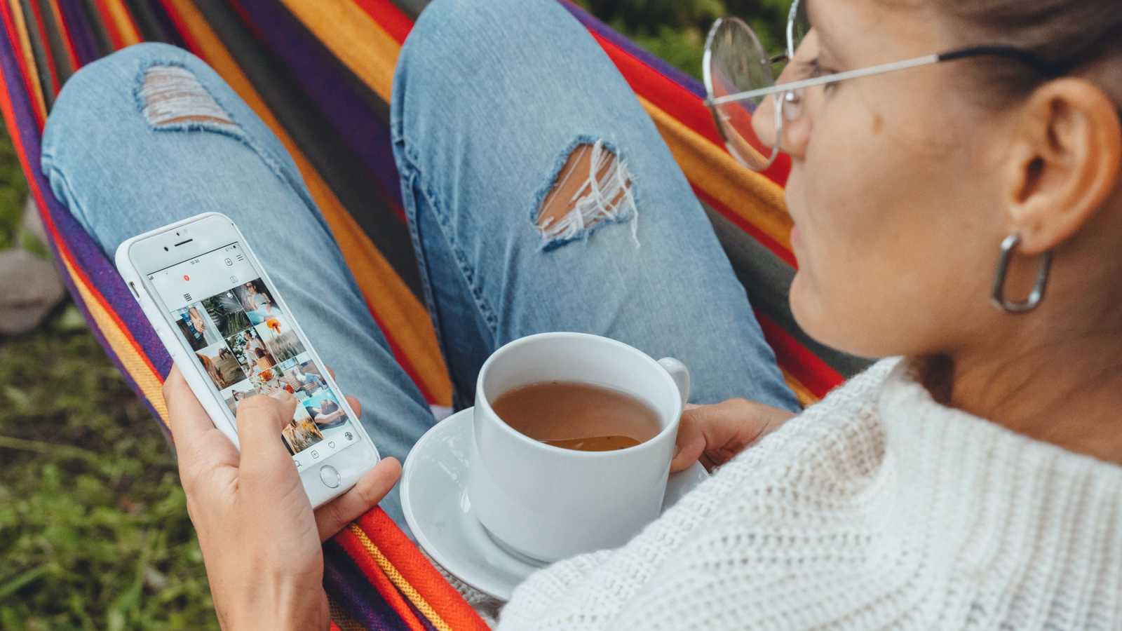 Millennial trendy blogger woman check Social media Instagram photo drink tea in hammock garden